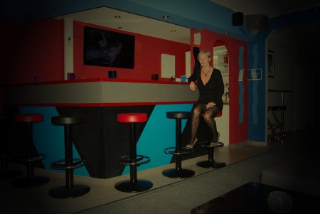 Bar mit roter und blauer Theke und schwarzen Hockern mit roten Sitzen.