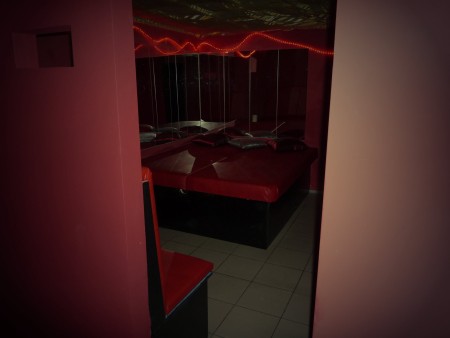 Blick durch eine Tür ins Spiegelzimmer, rote Liege und Spiegel mit Lichterkette.